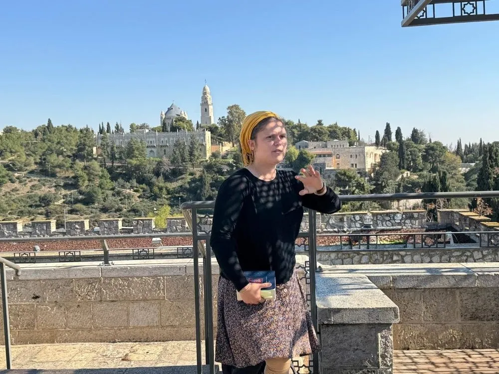 Orit guiding a tour with Mount Zion behind her
